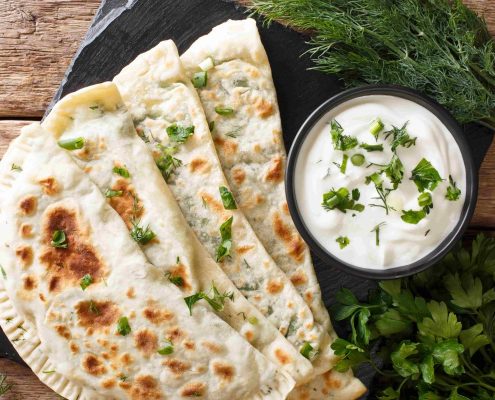 Typical-Turkish-meal-Gozleme-with-herb-and-cheese-on-slate-board-on-the-table.-Horizontal-top-view-from-abov-min